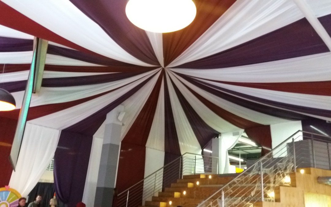 Event venue featuring a ceiling with radiating purple, burgundy, and white fabric draping by The Events Draping Co.