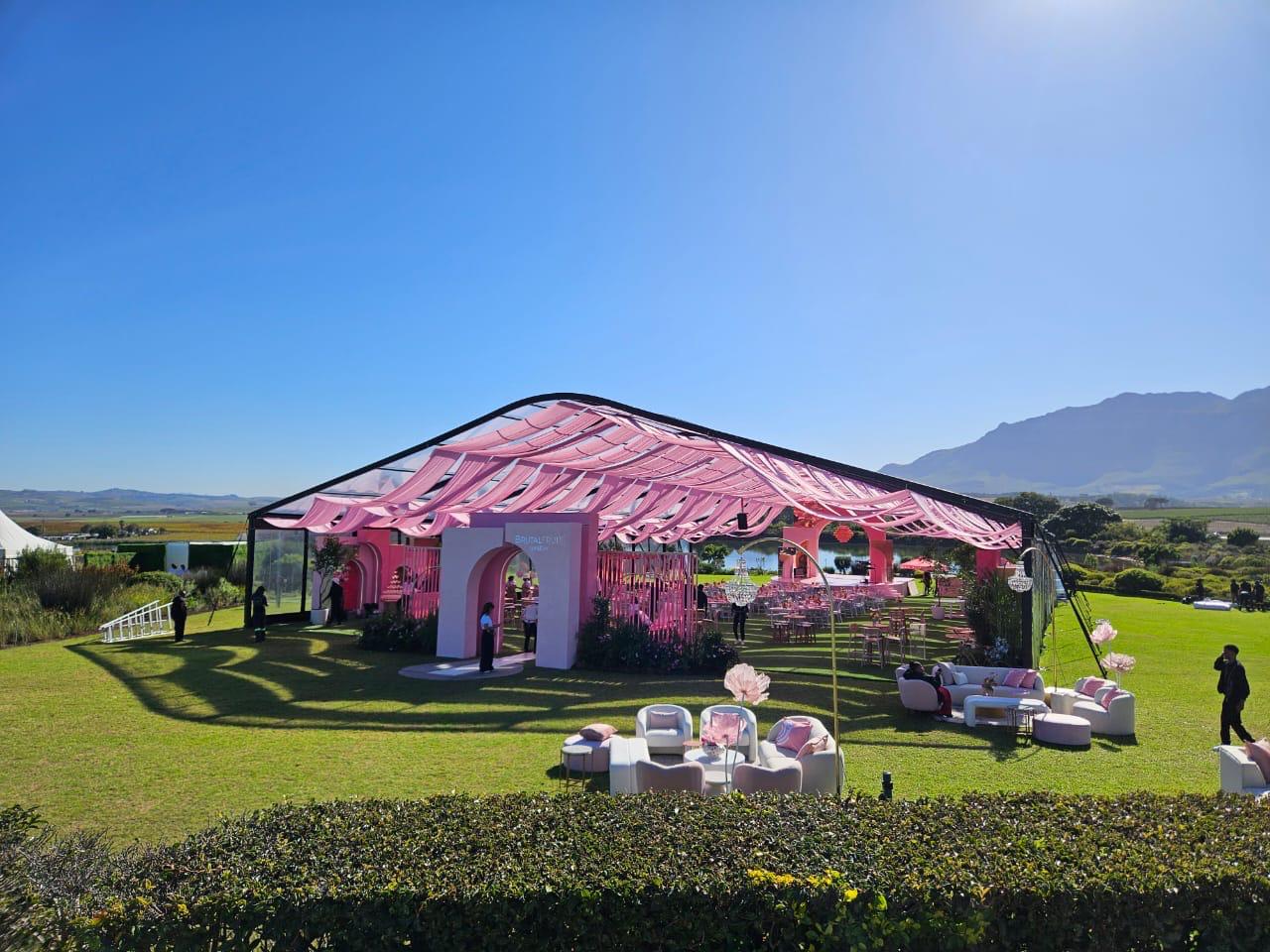 Transparent marquee draped with pink strips by The Events Draping Co.