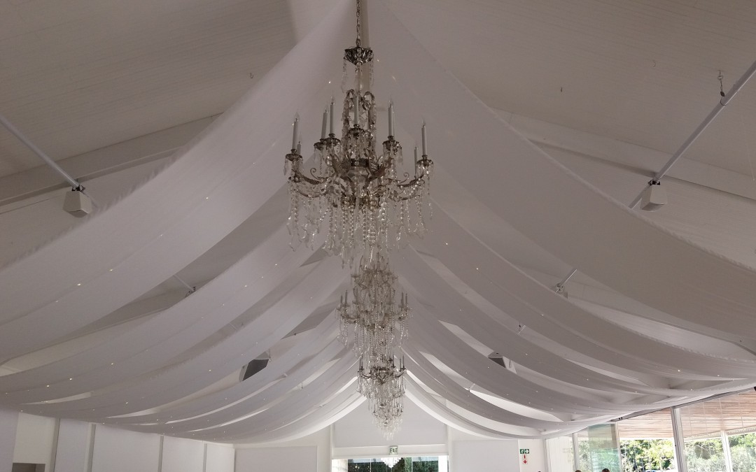 Wedding setup at Laurent, Lourensford Wine Estate, featuring strips of white fabric and fairy lights between chandeliers by The Events Draping Co.