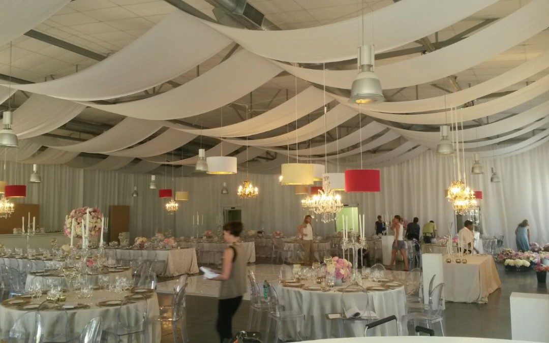 Pre-wedding Mehndi celebration at The Lookout, V&A Waterfront, featuring pink, orange, and purple ceiling strips, and a curtain of gold velour and mesh fabric by The Events Draping Co.
