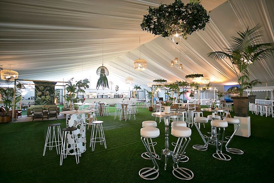 Large marquee, 30 meters by 65 meters, with a fully draped roof and sides, featuring elegant seating areas, greenery, and decorative lighting, by The Events Draping Co.