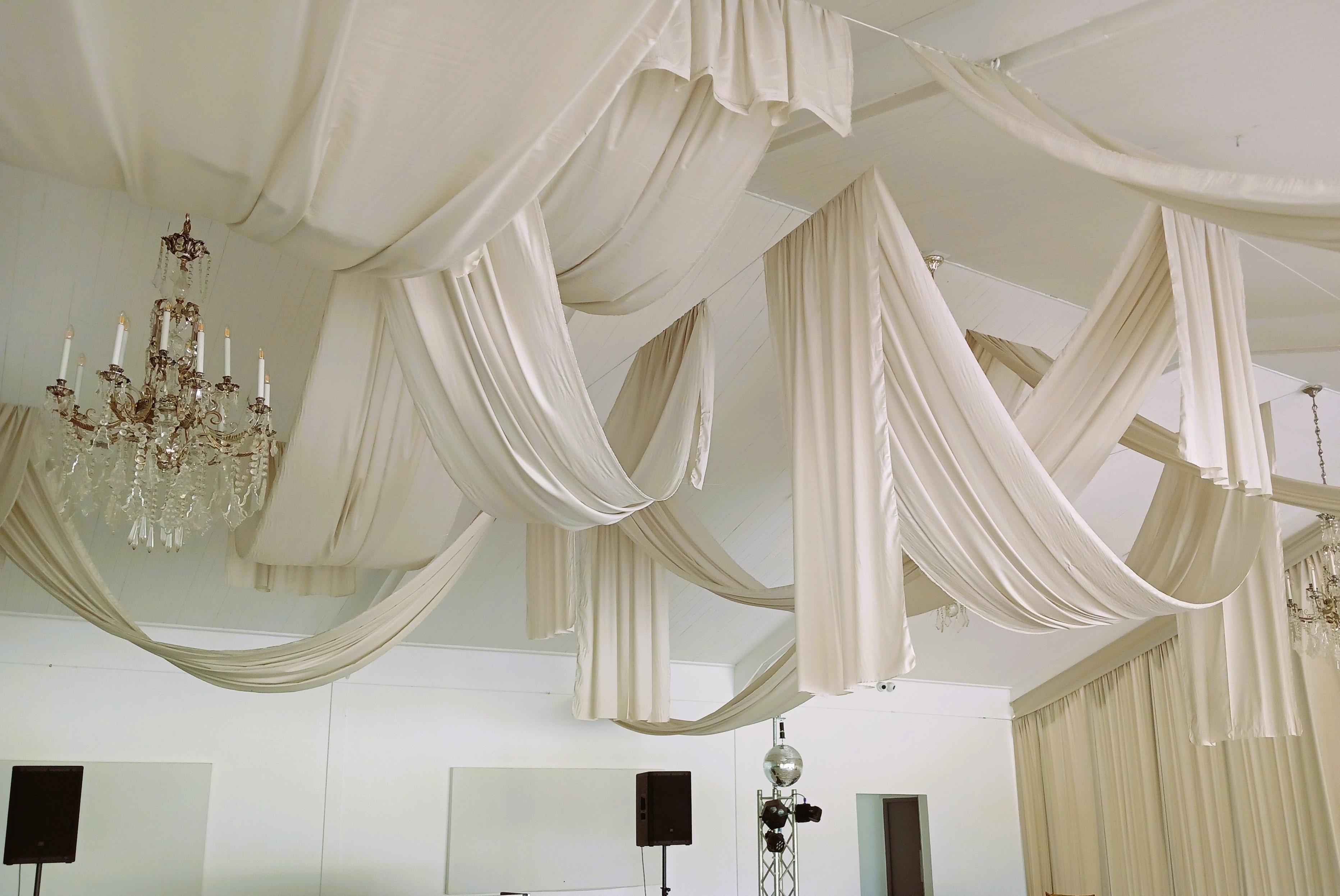 Elegant ceiling swags in cream fabric by The Events Draping Co., providing a sophisticated look for an indoor event.