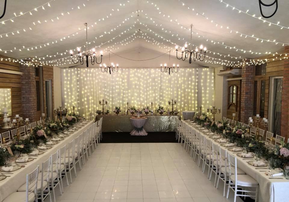 Wedding reception setup with white ceiling draping and fairy lights, creating a magical ambiance by The Events Draping Co.