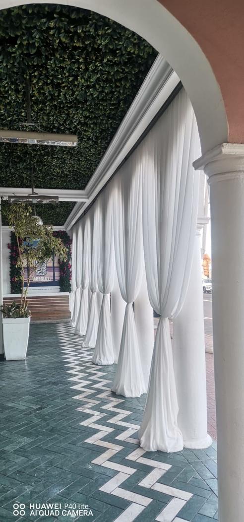 White chiffon tie-back draping swags at a series of pillars by The Events Draping Co.